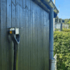 Et redskabsophæng i metal på en sort trævæg der holder 1 Haveredskab med et D håndtag. Lukket